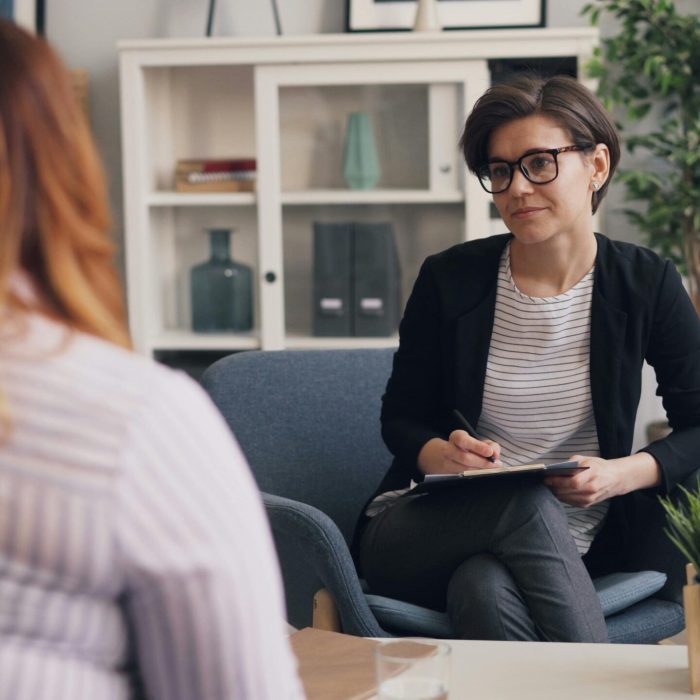 A therapist and patient having a counseling session in a modern office sitting area.